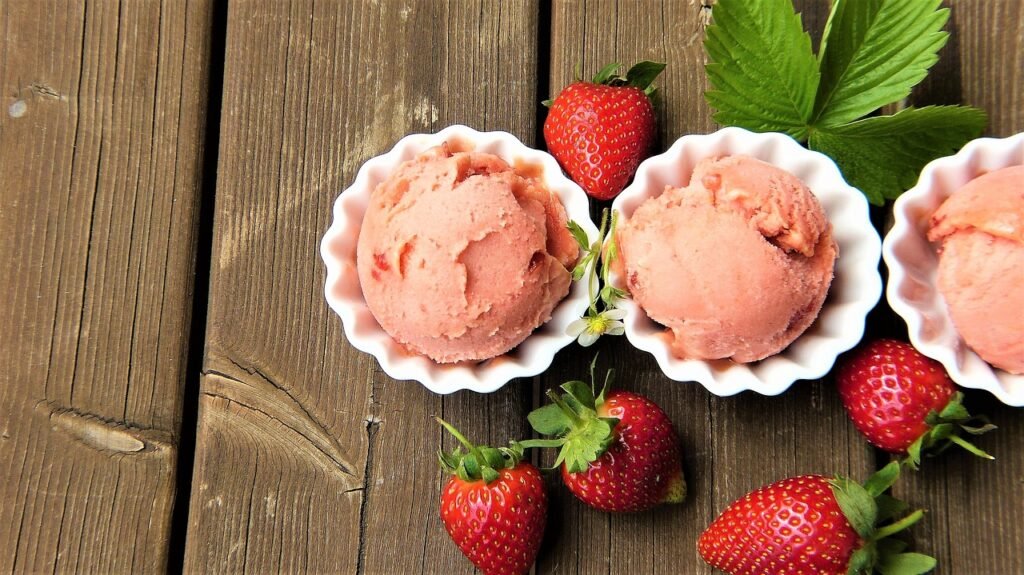 A scoop of homemade strawberry ice cream topped with fresh berries in a rustic bowl