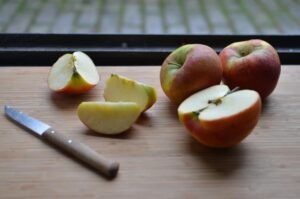 Freshly sliced apples on a wooden board by the window, showcasing natural light.