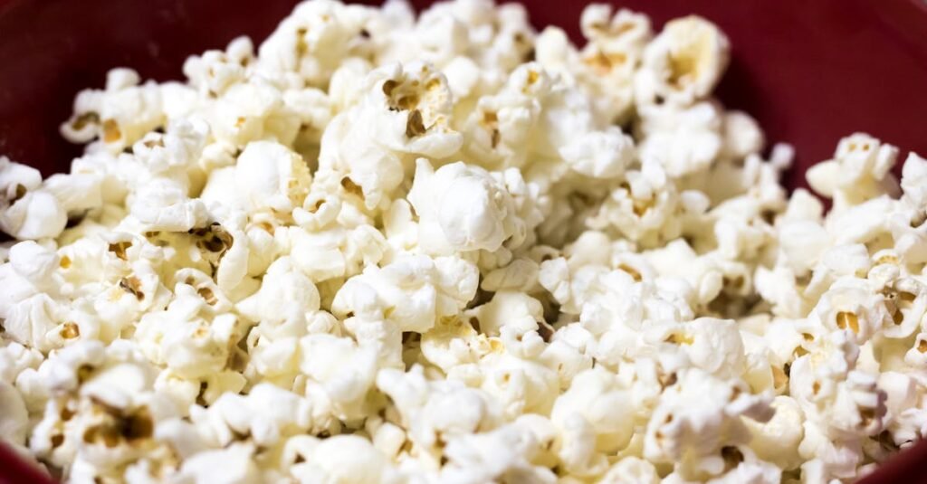 Delicious close-up of freshly popped popcorn in a red bowl, perfect for snacking.