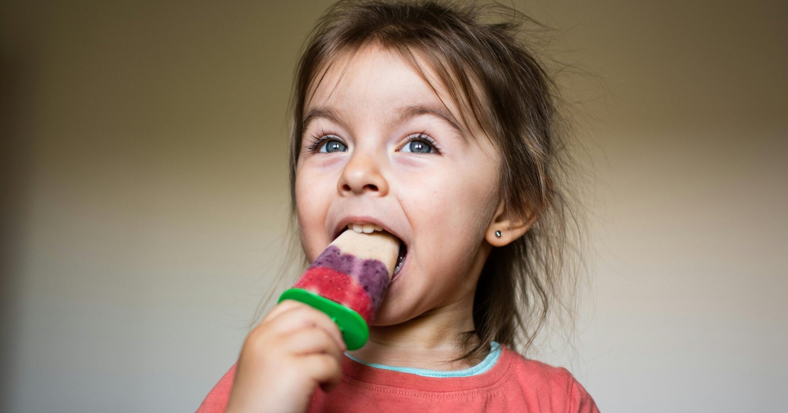 Adorable child savoring a homemade popsicle indoors, capturing a joyful moment.